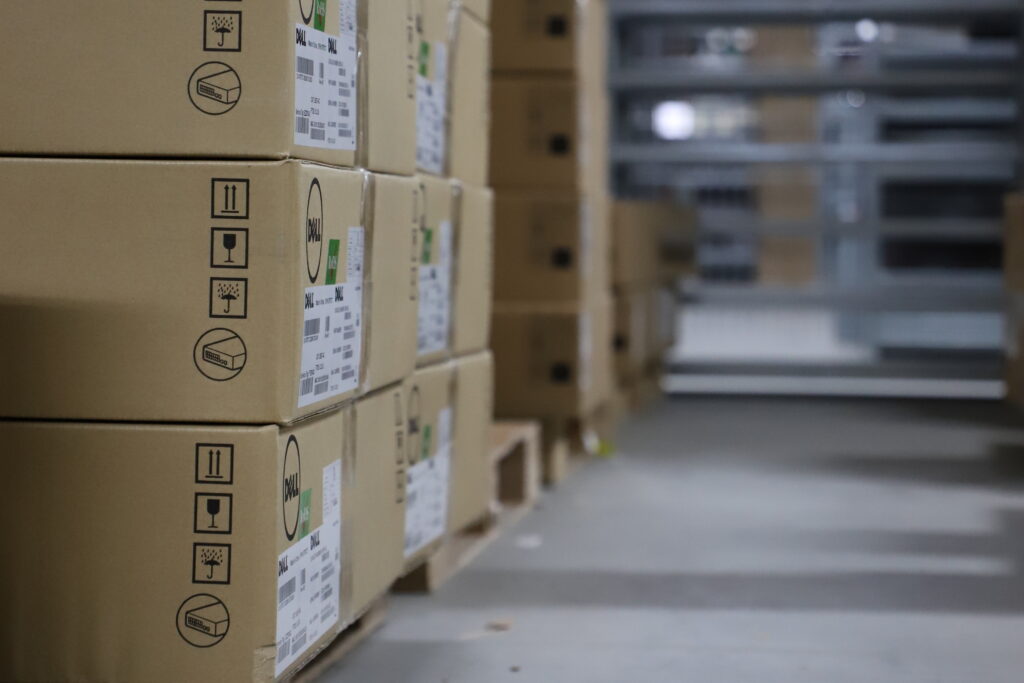 A large number of boxes are stacked neatly on pallets, containing components ready to be shipped